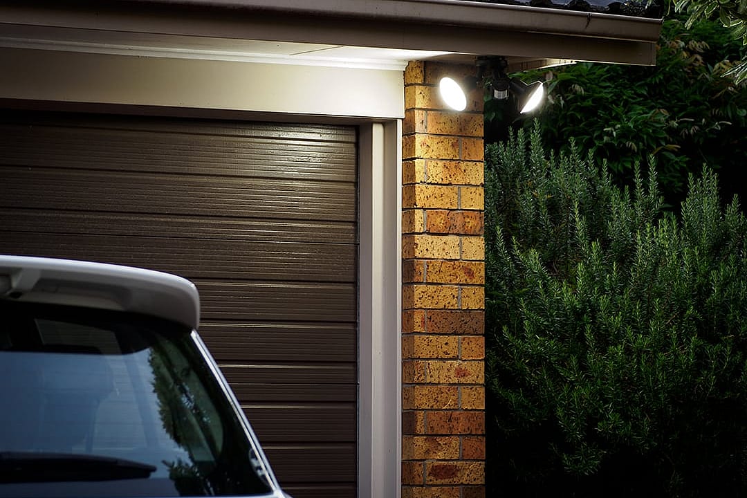 A view of a home's garage door at night with security lights.